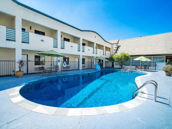 Outdoor pool and sun deck with green umbrellas at Mikado Hotel