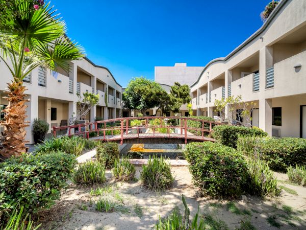 Tranquil garden courtyard with a wooden footbridge at Mikado Hotel