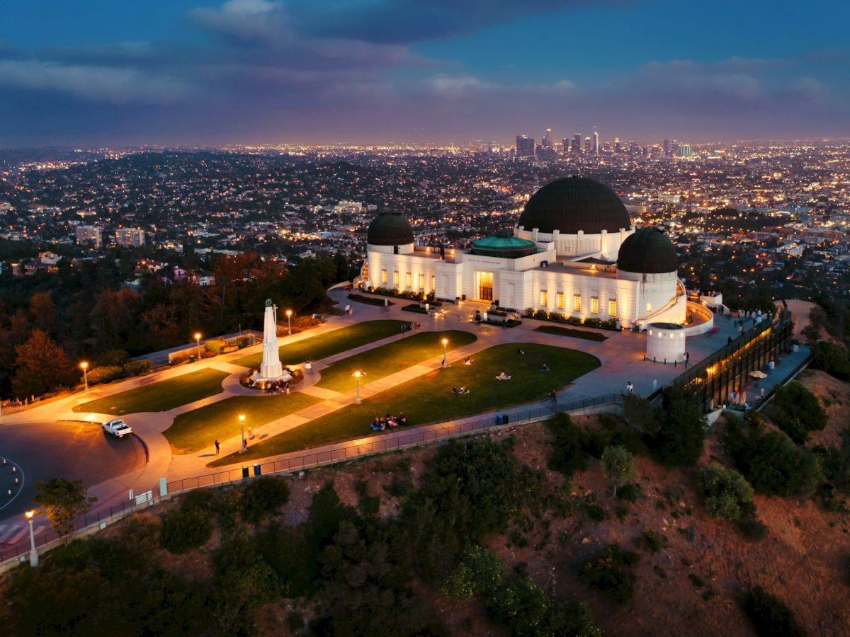Griffith Observatory lit up at dusk above the lights of Los Angeles
